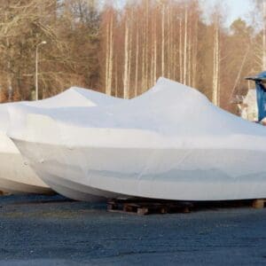 A boat covered in tarps on the ground.