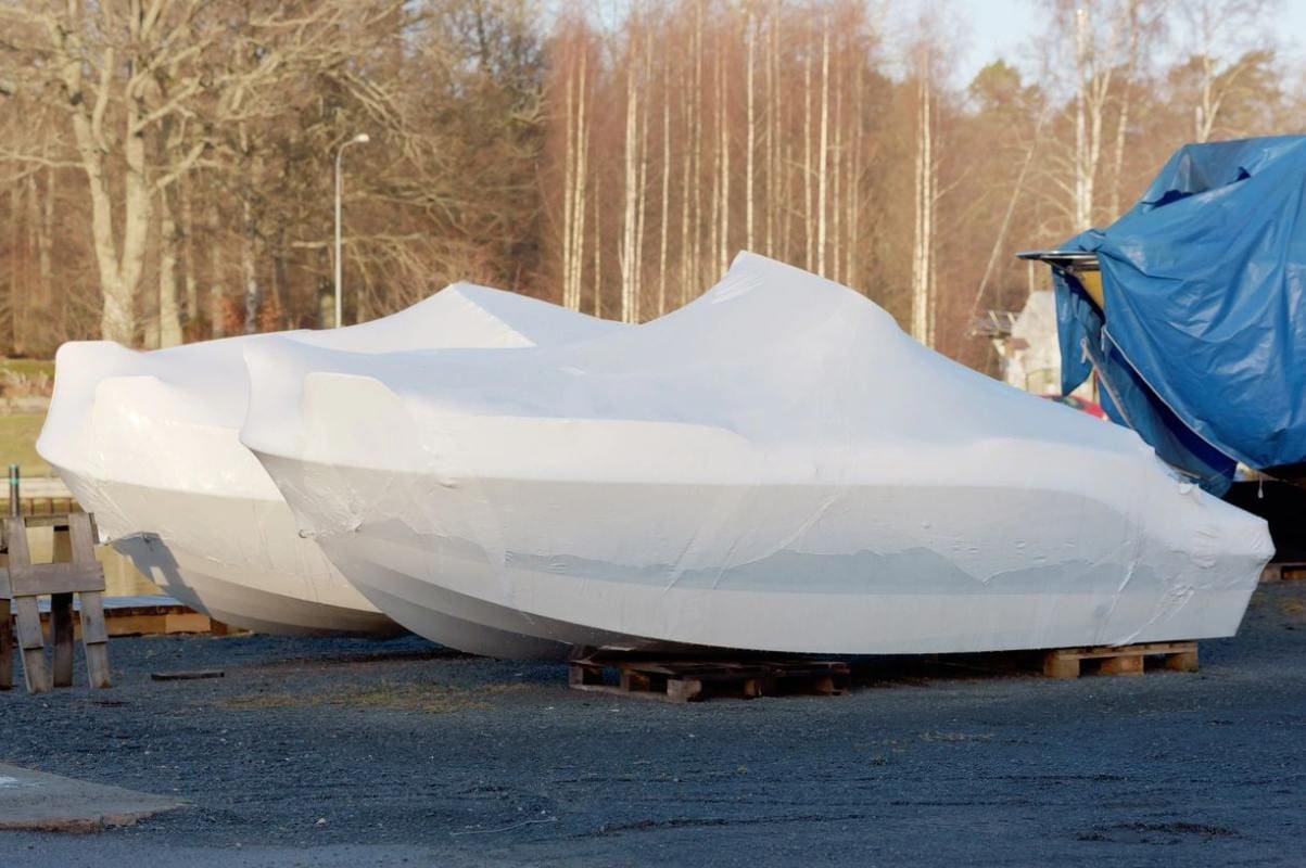 A boat covered in tarps on the ground.
